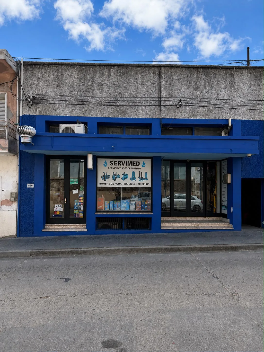 Fachada azul del local de SERVIMED en Gral. José G. Artigas 660, San José de Mayo, con el cartel “Bombas de agua, todos los modelos”