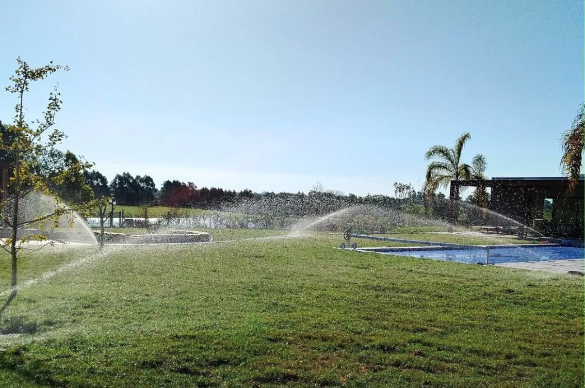 Sistema de riego de SERVIMED funcionando en el césped de una casa con piscina